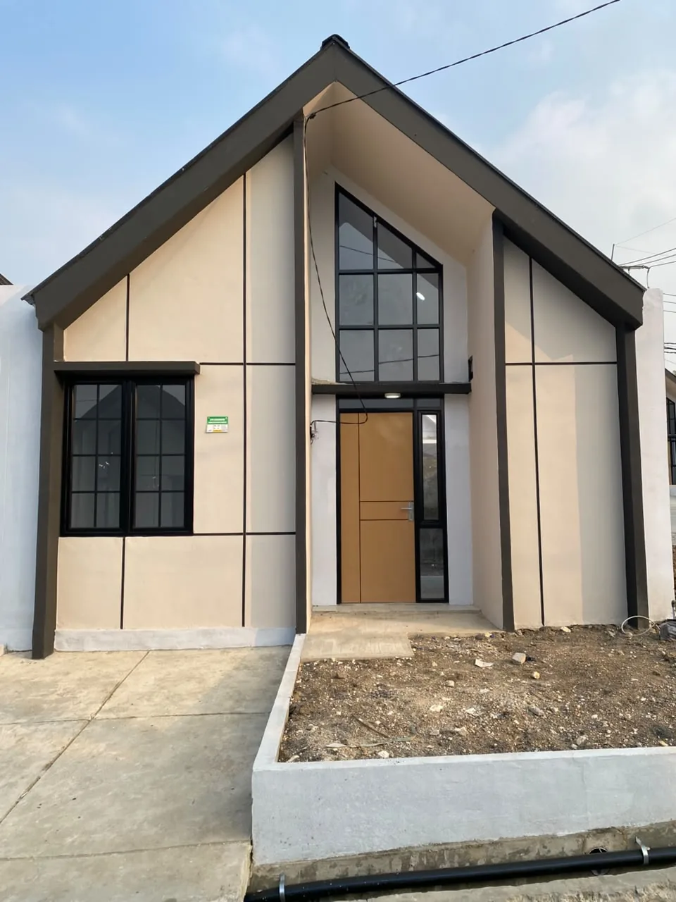 Fasad rumah Sajiva yang telah dibangun, dengan pintu kayu dan jendela tinggi